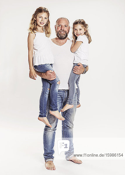 Portrait of happy man with his two daughters in front of white background