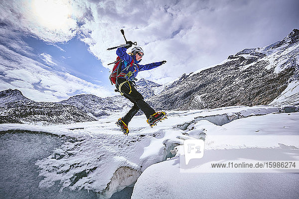 Female mountaineer jumping over crevasse  Glacier Grossvendediger  Tyrol  Austria