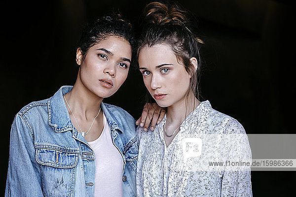 Portrait of two young women in front of black background