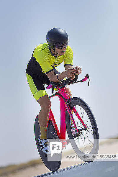 Confident cyclist riding bicycle on road against clear blue sky at desert in Dubai  United Arab Emirates