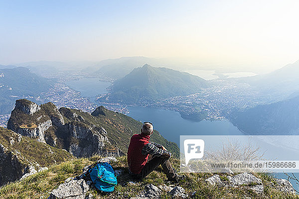 Rear view of hiker sitting on mountaintop  Orobie Alps  Lecco  Italy