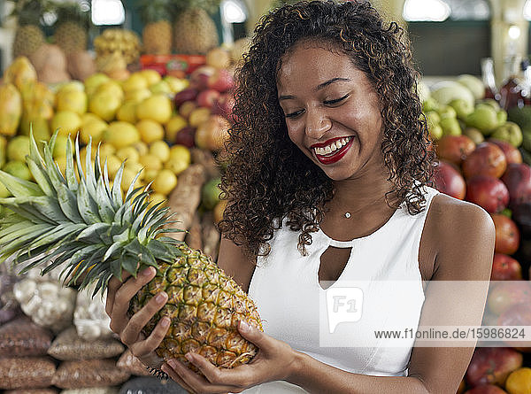 Porträt einer lächelnden Frau mit Ananas in der Markthalle