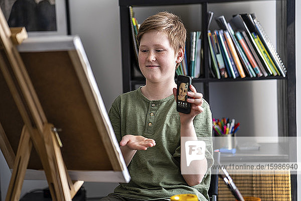 Boy showing via smartphone painting to mother