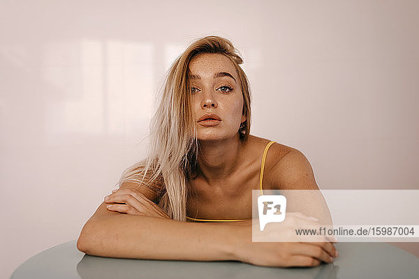 Schöne junge blonde Frau lehnt sich zu Hause an den Tisch