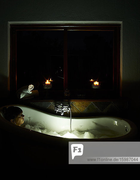 Frau entspannt sich nachts in der Badewanne