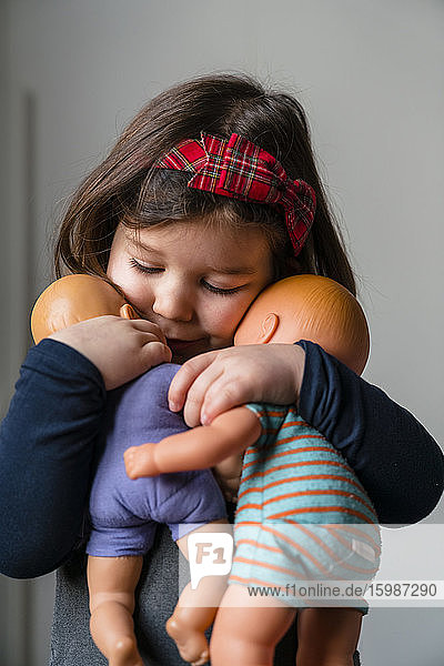 Nahaufnahme eines süßen Mädchens  das seine Puppen zu Hause umarmt