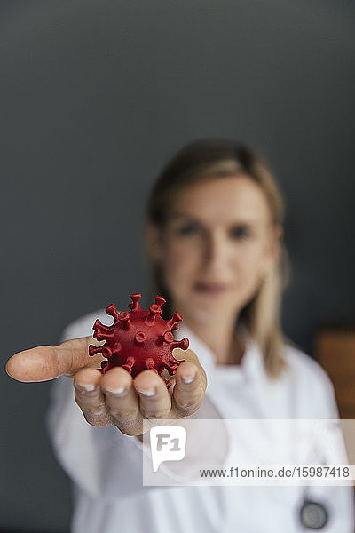 Hand einer Wissenschaftlerin  die ein 3D-Modell des SARS-CoV-2-Virus hält  Nahaufnahme