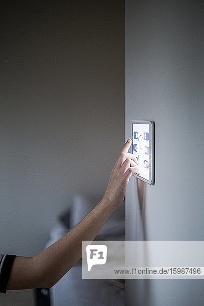 Beschnittenes Bild eines Jungen mit einem digitalen Tablett  das zu Hause an der Wand befestigt ist