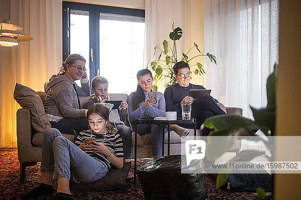 Familie nutzt drahtlose Technologien im Wohnzimmer und entspannt auf dem Sofa im modernen Zuhause