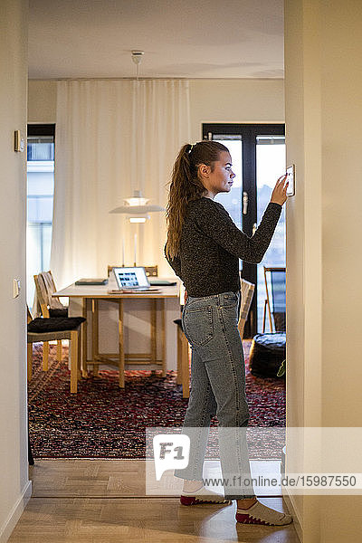 Teenager-Mädchen in voller Länge mit digitalem Tablett an der Wand in einem modernen Haus