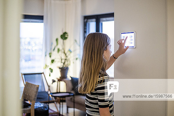 Mädchen mit digitalem Tablett an der Wand im modernen Haus