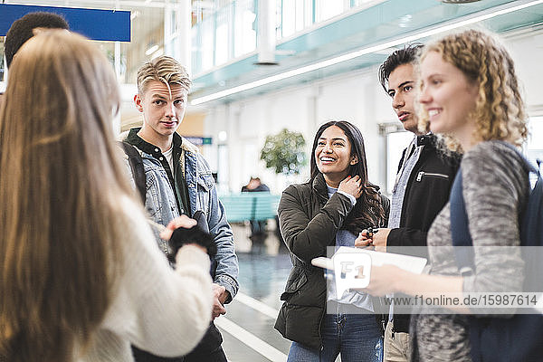 Young male and female students talking while standing in cafeteria at university