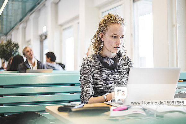 Seriöse Studentin benutzt Laptop in Cafeteria
