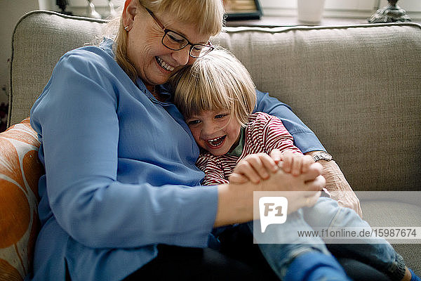Glücklicher Junge sitzt zu Hause mit der Großmutter auf dem Sofa