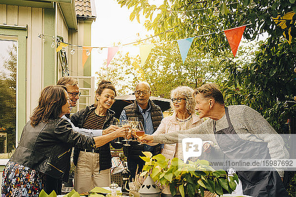 Aktive männliche und weibliche Seniorenfreunde mit feierlichem Toast im Hinterhof während einer Gartenparty