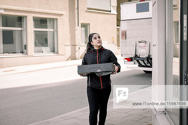 Junge Zustellerin liefert Paket im Gebäude ab