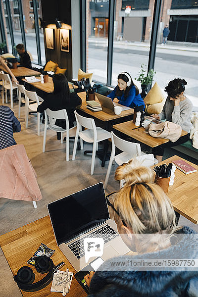 High angle view of customers sitting at tables in coffee shop