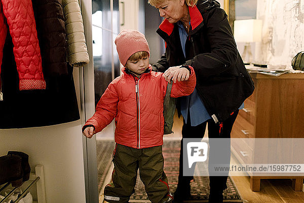 Ältere Frau hilft Enkel beim Tragen der Tasche zu Hause