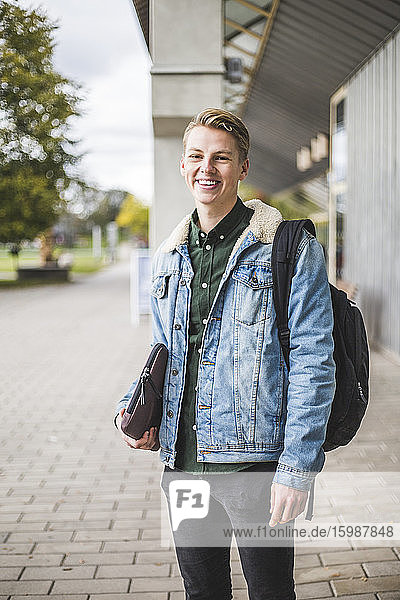 Portrait of smiling young woman standing at university campus