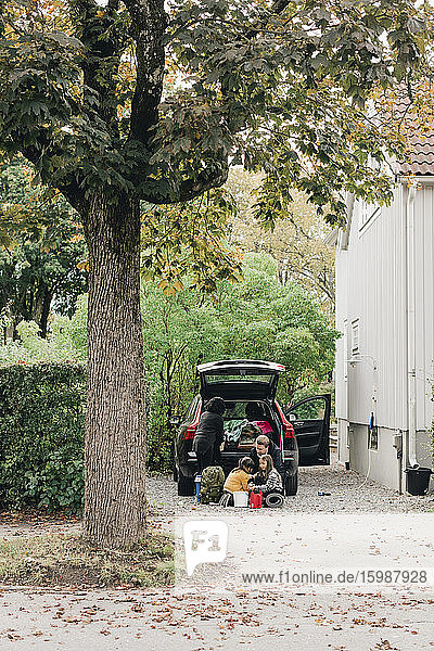 Familie lädt Gepäck in den Kofferraum eines Elektroautos  während sie zum Picknick fährt