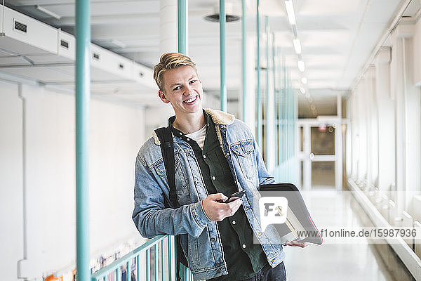 Portrait of happy young male student in corridor of university