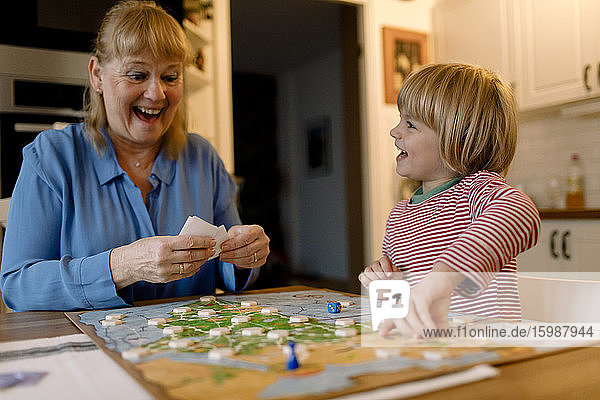 Fröhliche Großmutter und Enkel spielen zu Hause Brettspiel