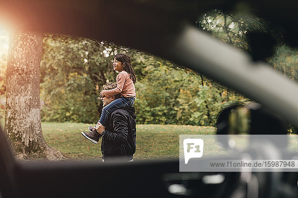Vater trägt glückliche Tochter beim Picknick am Wochenende auf den Schultern