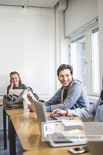 Smiling young man studying in university classroom