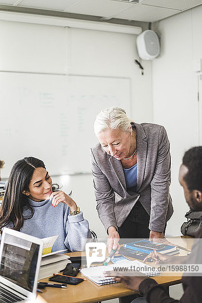 Reife Lehrerin erklärt Schülern im Klassenzimmer