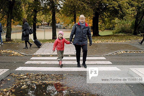 Großmutter geht mit ihrem Enkel auf einem Fußweg in der Stadt