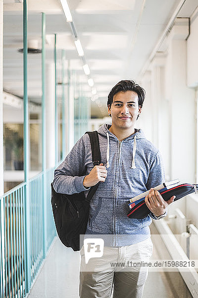 Porträt eines lächelnden männlichen Studenten im Korridor der Universität
