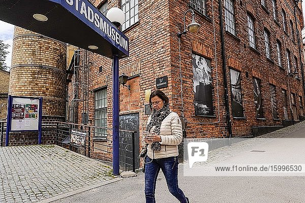 Norrkoping Sweden Pedestrians walking in the old iconic mill and industrial section of town and the Museum of Work.