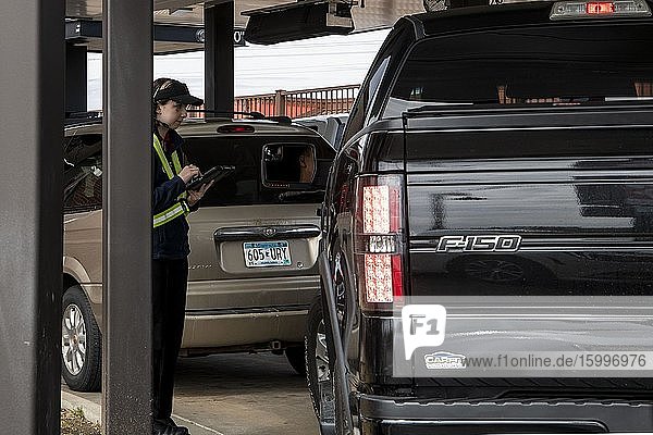 Maplewood Minnesota. An employee in a fast food restaurant taking orders outside from customers at a safe distance due to the dining room being closed because of the coronavirus pandemic.