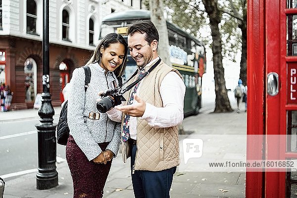 Happy traveling couple looking at photos on their camera  London  Great Britain