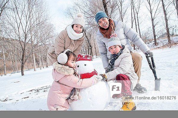 Glückliche Familie macht einen Schneemann im Schnee
