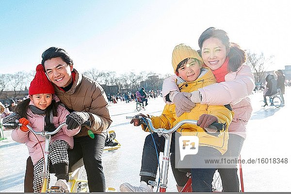 Das Glück einer vierköpfigen Familie beim Spielen auf der Eislaufbahn