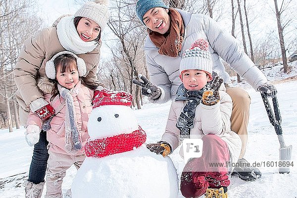 Glückliche Familie macht einen Schneemann im Schnee