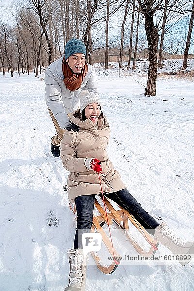 The young couple sledding in the snow