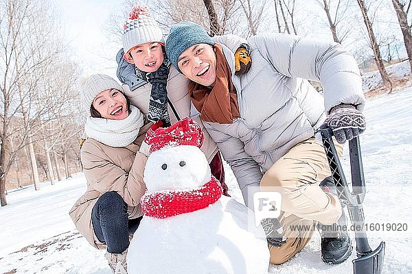 Happy family make a snowman in the snow