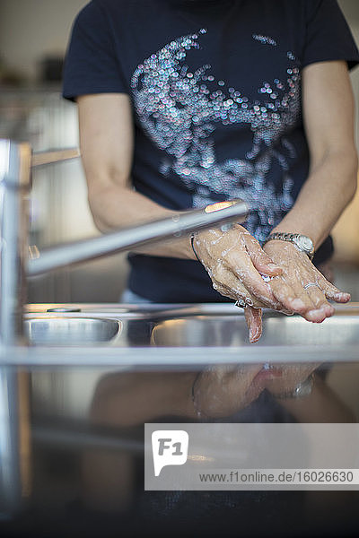 Frau wäscht Hände an der Küchenspüle