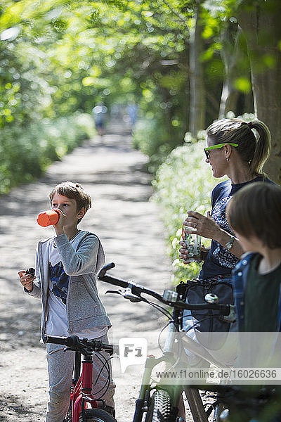 Mutter und Söhne trinken Wasser beim Radfahren