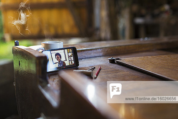 Video-Chat mit Kollegen per Smartphone auf einem Holzboot