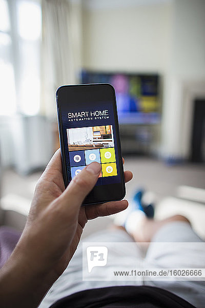 POV Mann nutzt Hausautomatisierung auf Smartphone im Wohnzimmer