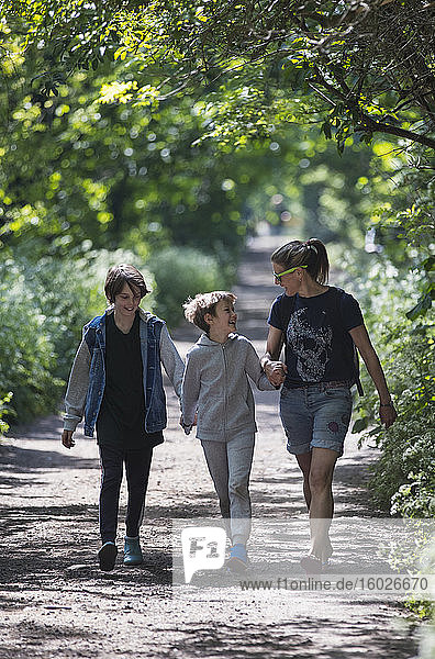 Mother and sons walking on sunny park path