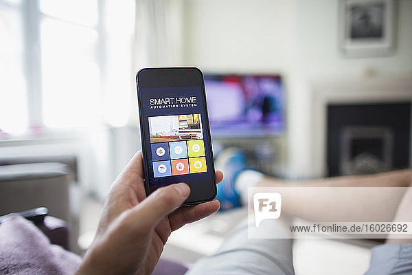 POV-Mann überprüft Haustechnik auf Smartphone im Wohnzimmer