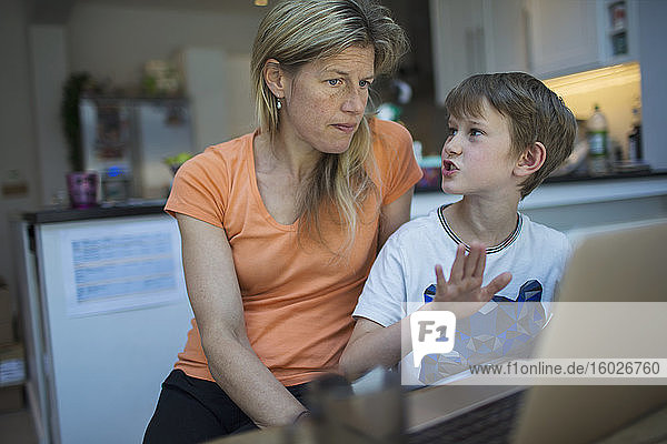 Mother and son using laptop at home