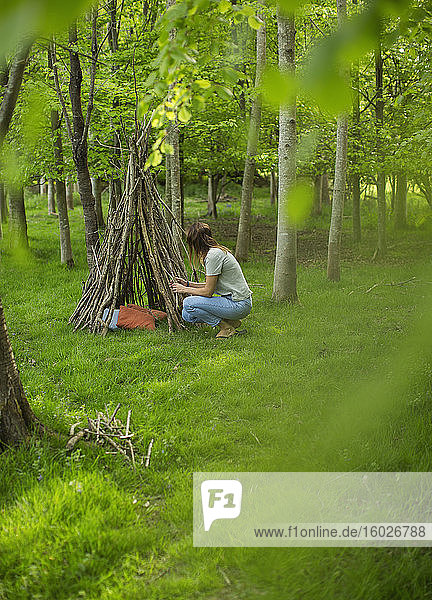Frau macht Ast-Tipi im Wald