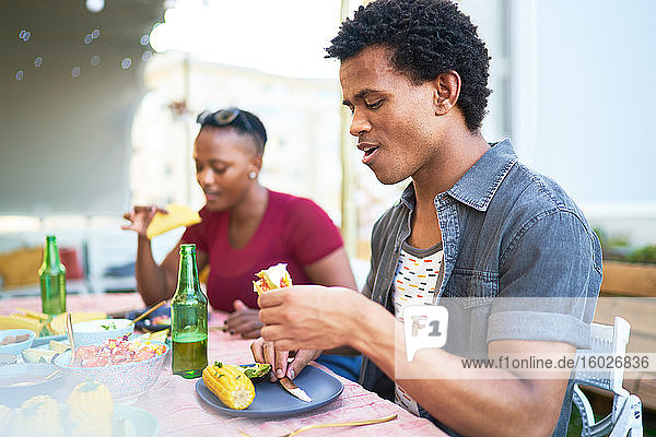 Junger Mann isst Taco-Mittagessen am Terrassentisch