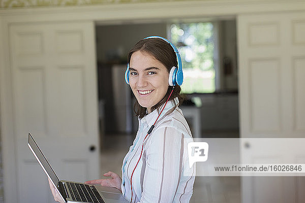 Porträt eines selbstbewussten Teenagers mit Kopfhörer und Laptop