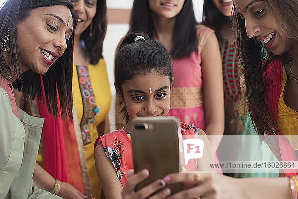 Indische Frauen und Mädchen in Saris und Bindis mit Smartphone